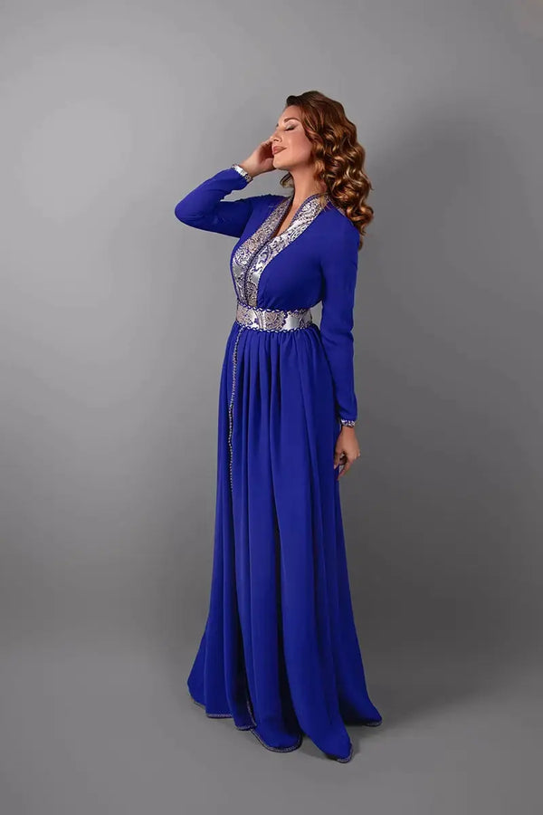 Zijaanzicht van de koningsblauwe caftan die de geborduurde afwerkingen en de elegante snit benadrukt.