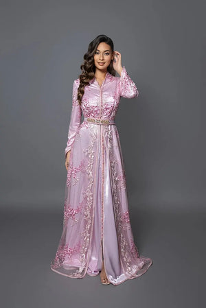 Modelo luciendo el caftán Aydene rosa claro con bordados florales, silueta femenina y acabados lujosos para eventos y ceremonias.