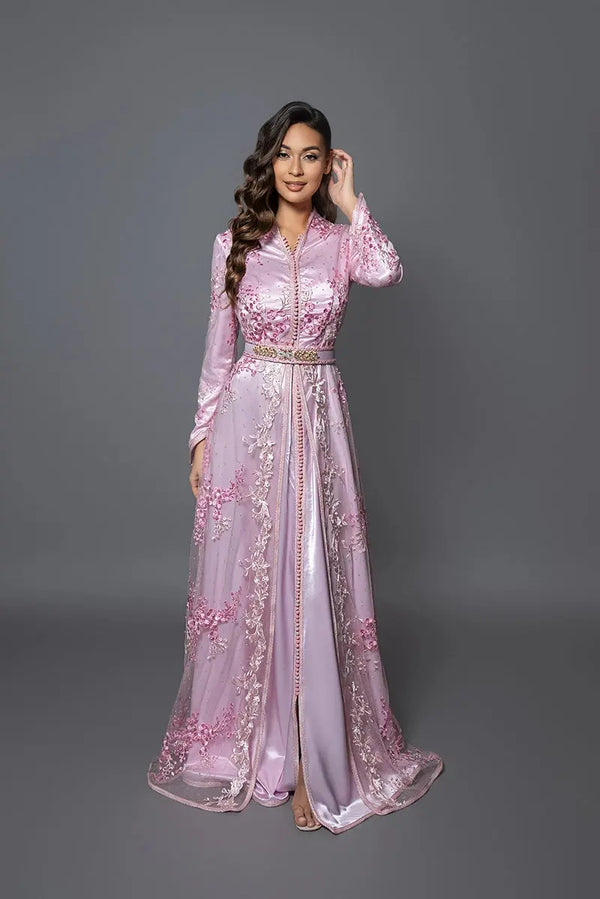 Modelo luciendo el caftán Aydene rosa claro con bordados florales, silueta femenina y acabados lujosos para eventos y ceremonias.