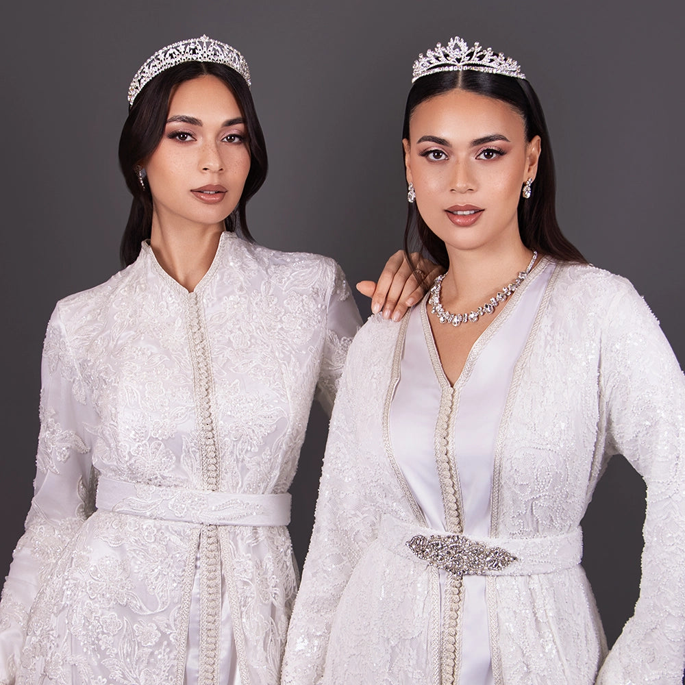 Takchita en dentelle perlée blanche portée par deux jeunes mariées avec diadème argent sur la tête.